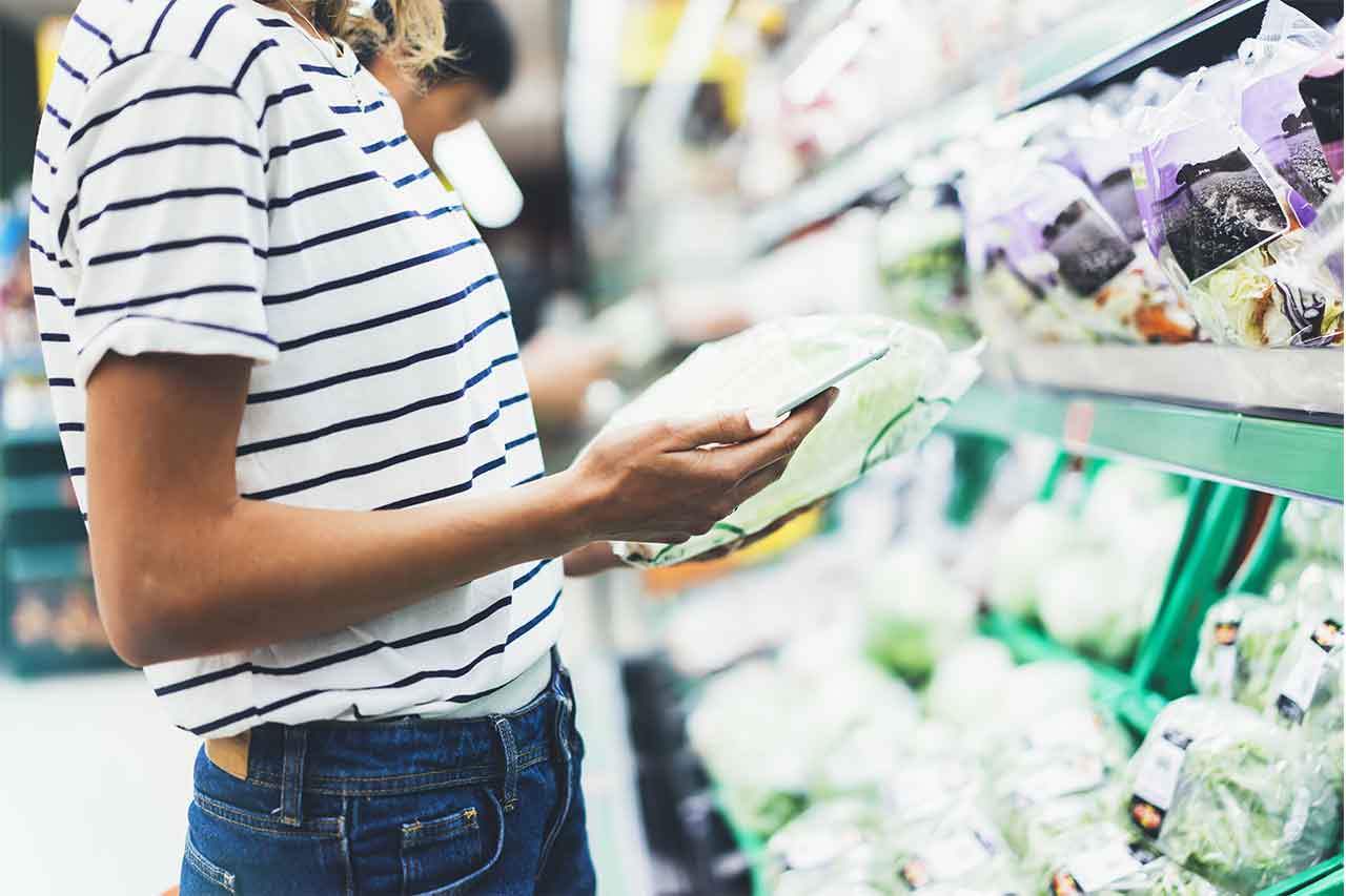 Lady looking at her phone while grocery shopping.