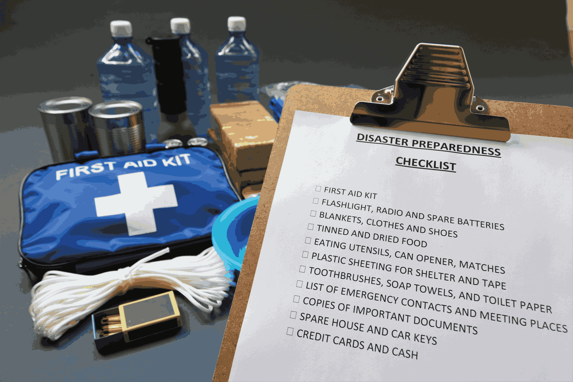 Disaster preparedness checklist with supplies in the background